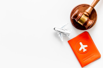 Flight cancellation. Airplane, passport, judge gavel on white desk top-down copy space