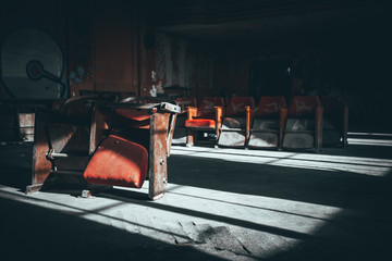 Sare, zniszczone fotele w ciemnym, opuszczonym kinie w blasku promieni słonecznych