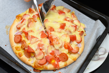 housewife cutting a homemade fresh cooked pizza