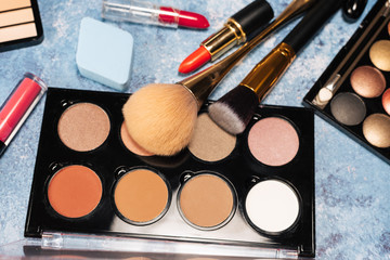 Various makeup products, brushes on blue background