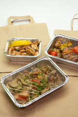 Close-up of a ready meal for delivery and a paper bag on a white background.