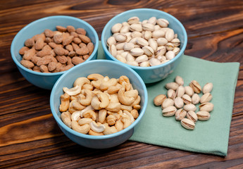 Mix of nuts on a old rustic table. Gold pistachios, cashews, almond