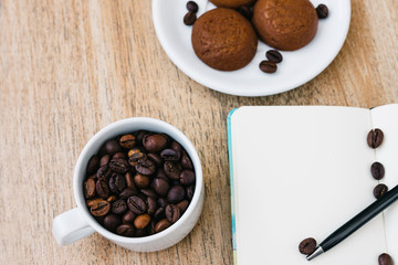 Flat lay composition with notepad, cup of coffee and breakfast cookies. Record a plan for the day. Morning workplace