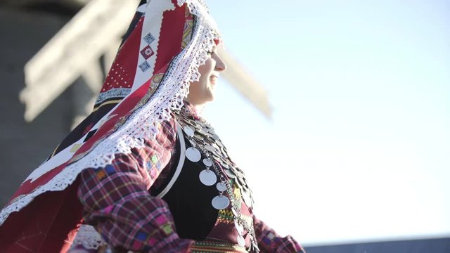 People in traditional russian clothes dancing outdoor on traditional antique wooden windmill background. Group of happy people wearing national Finno-Ugric clothes.