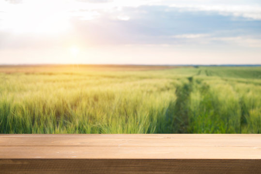 wood board table in front of field of wheat on sunset light. Ready for product display montages