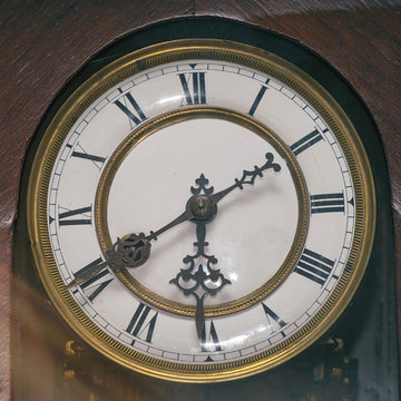 Dial of an old wooden wall clock with Roman numerals