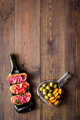 Antipasto on wine bottles on wooden table top-down copy space