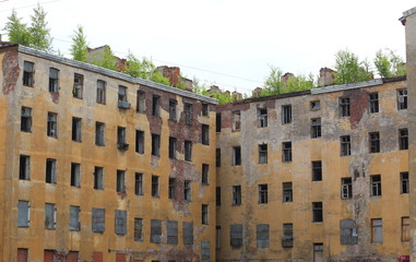 The ruins of an old apartment building with trees on the roof