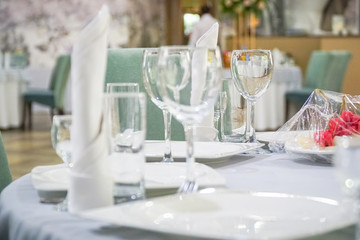The table in the restaurant is served for lunch. On a table with a white tablecloth, empty wine glasses, a plate, napkins. Selective focus