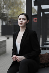 young caucasian woman in  black suit sit alone outdoor