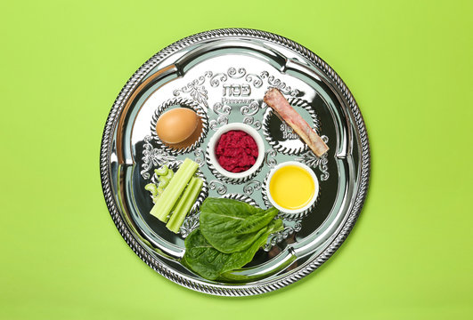 Passover Seder plate (keara) with symbolic meal on green background, top view. Pesah celebration