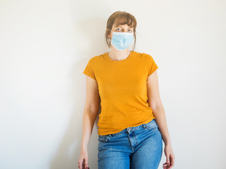 Young caucasian woman in yellow T-shirt wearing protective face mask to face virus spreading or pollution.