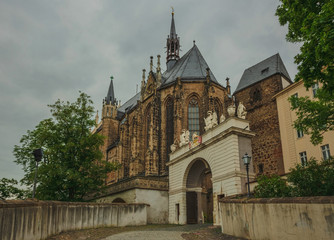 The front arch is decorated with a coat of arms and sculptures, the castle Church with a spire against a cloudy sky. Altenburg Castle. Germany. Soft focus, blurry background.