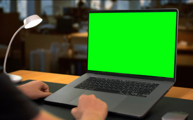 Man sitting by table with laptop Green Screen mock up