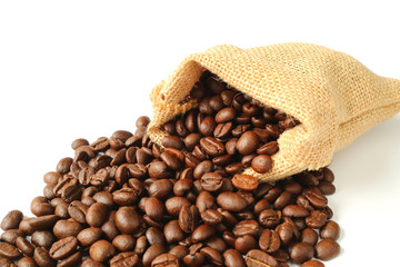 Roasted coffee beans scattered from burlap bag on white background