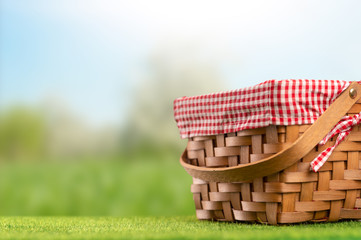 Obraz premium On green grass, a picnic basket against the backdrop of the landscape. A backdrop for relaxing and spending the weekend. Picnic and relaxation