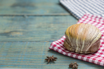 fresh bread put on red.scottish pattern fabric with grains on old wooden table background.With copy space and selective focus.
