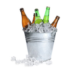 Metal bucket with bottles of beer and ice cubes isolated on white © New Africa
