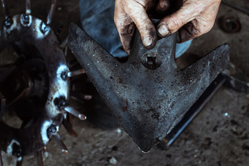 Man repairing tractor plow. Mechanic concept, agricultural technology.