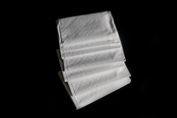 Disposable white paper napkins on a black background. Compliance with the safety rules against...