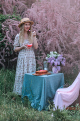 Fototapeta premium Beautiful young girl in pink has breakfast on a background of rosewood.