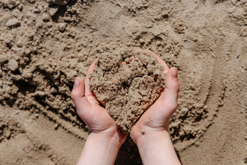 baby hands holding heart shaped sand