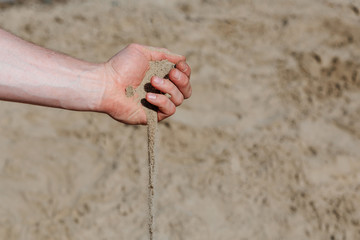 Photo of a hand from which sand is pouring.
