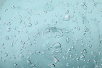 Pure transparent cosmetic gel on light blue background, closeup