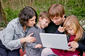 Young parents with their children study in a flowering garden. Against the background of green grass. A happy family.