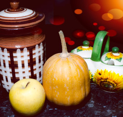 apple with pumpkin near the jar and saucer stand on the table, and nearby visible glare of light