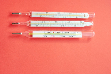 three medical thermometers lie on red background