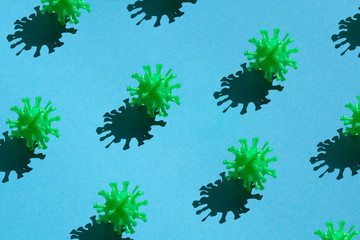 Many green models of coronavirus with a hard shadow on a blue background. Concept pattern on the theme covid-19