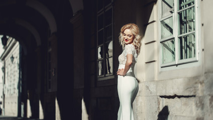 Portrait of Beautiful Happy Curly Blond Hair Bride. the bride stands in the arch of an old house