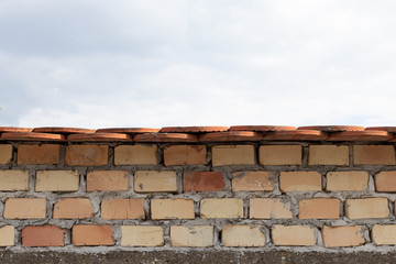 brick fence with tiles and cloudy sky