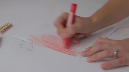 Woman coloring a piece of paper with a red crayon - Powered by Adobe