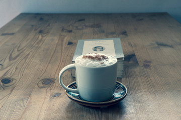 cup with coffee and a closed book on a rustic wooden table