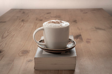 cup with coffee and a closed book on a rustic wooden table