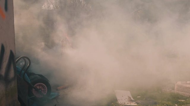 Wide shot tracks in to reveal a smoke bomb explode in a Post- apocalyptic world