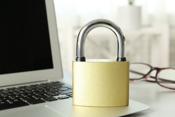 Metal lock and laptop on table, closeup. Protection from cyber attack