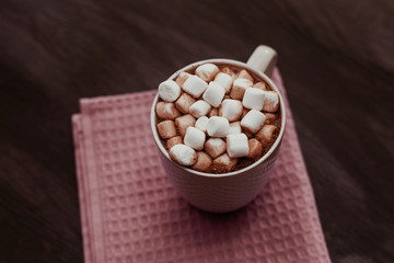 cocoa with marshmallow in a white mug on the table, home comfort