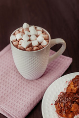 cake anthill on a plate on the table, cocoa with marshmallow in a white mug, home comfort