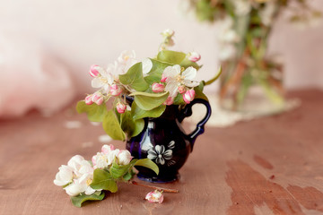 Beautiful still life with apple blossom and branches in jug at a white and pink wall on a wooden table