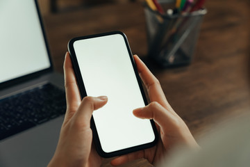Closeup of young woman hand holding smartphone on the table and the screen is blank, social network concept..