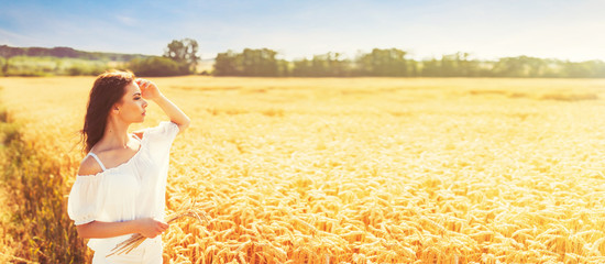 Beauty romantic girl enjoying nature in outdoors. Happy young woman in white shorts holding the ears on the field of golden ripe wheat in sun light. Free summer dreams © Digihelion