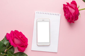 Mobile phone and dark pink rose on a pink background
