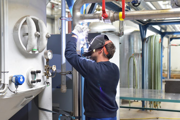 Schweißrer repariert Anlage in einer Fabrik // welder works in steel construction and repairs an...