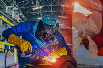 Industrial Worker at the factory welding process close up with protective equipment mask, PPE marks...