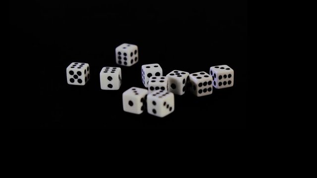 White cubes fall out, fly out on a black background for the game. Dice fall, rotate and bounce on a black surface. Stops in sight. Concept of business and casino or gambling. Close-up.