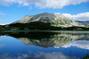Naklejka na ściany i meble Reflection of rocky Todorka peak in the calm water of Muratovo lakes in Pirin mountain National park in Bulgaria 