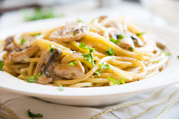 Spaghetti pasta with mushrooms, creamy sause and parsley on white
